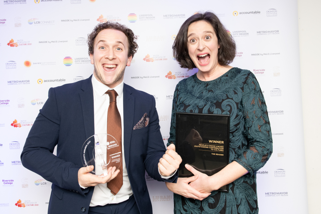 two excited people smiling holding an award