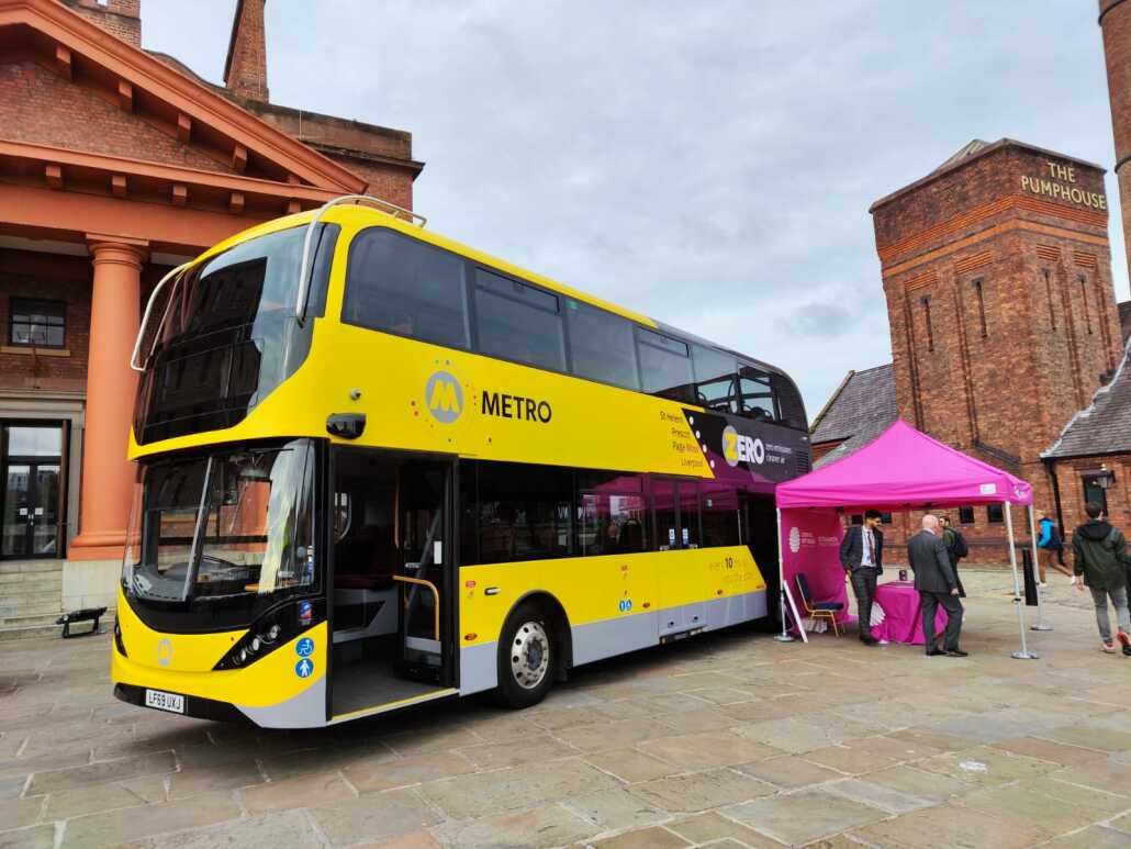 A yellow bus on show in front of buildings