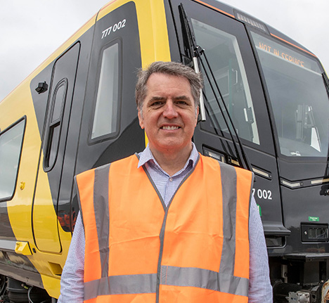Mayor Steve Rotheram standing in front of a new publicly owned battery powered train