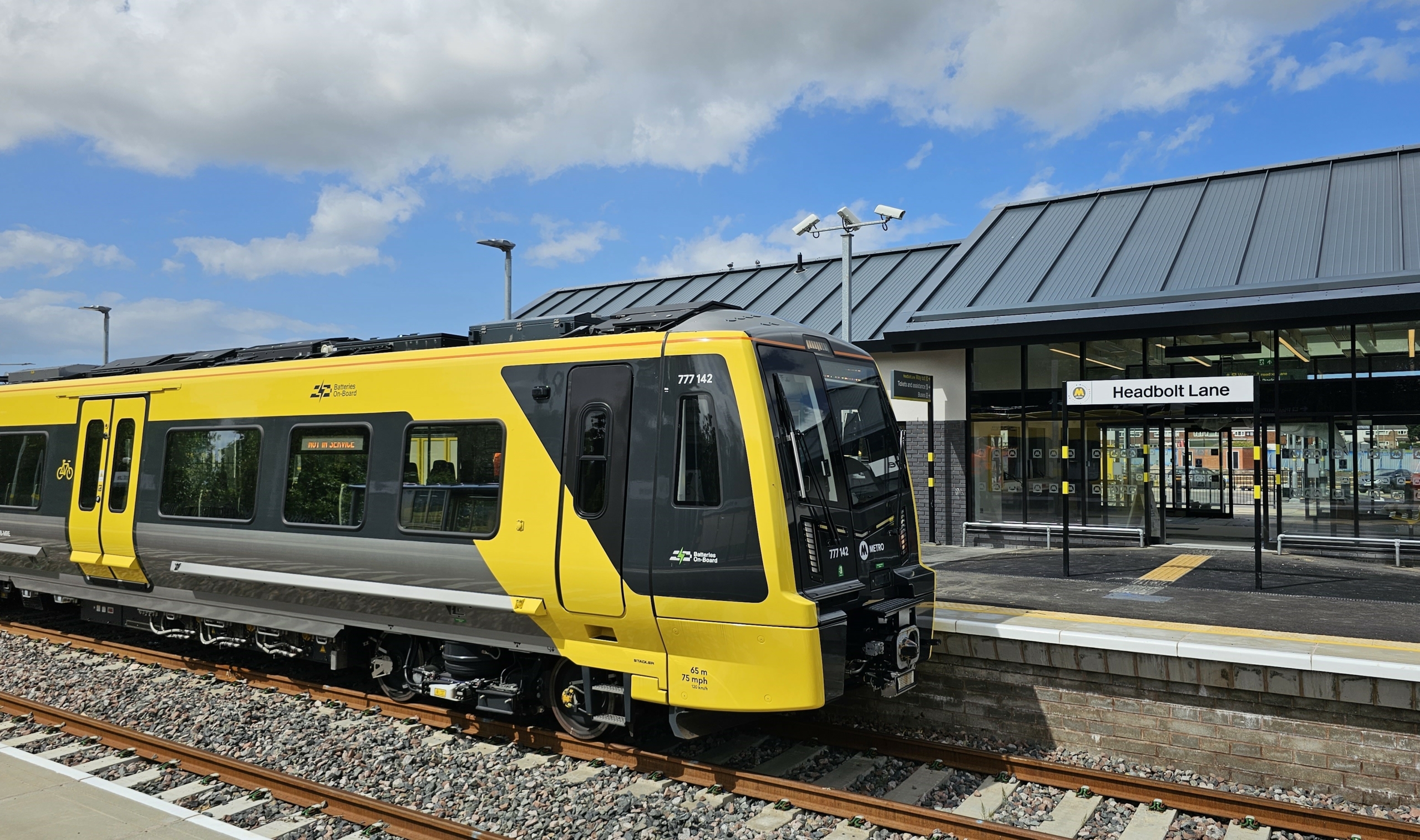 A battery powered train pulling in at the new Headbolt Lane station