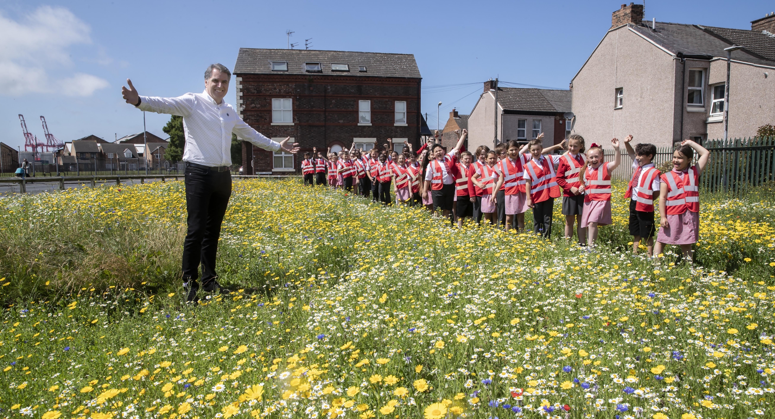 Mayor Steve Rotheram in a field of wildflowers with the children who sowed them.