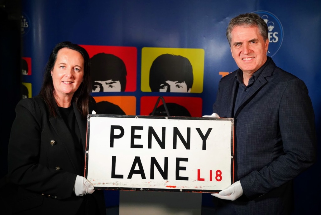 The returned Penny Lane Street sign stolen in 1976 being held by Mary Chadwick from the Beatles Story on the left hand side and Mayor Steve Rotheram on the right.