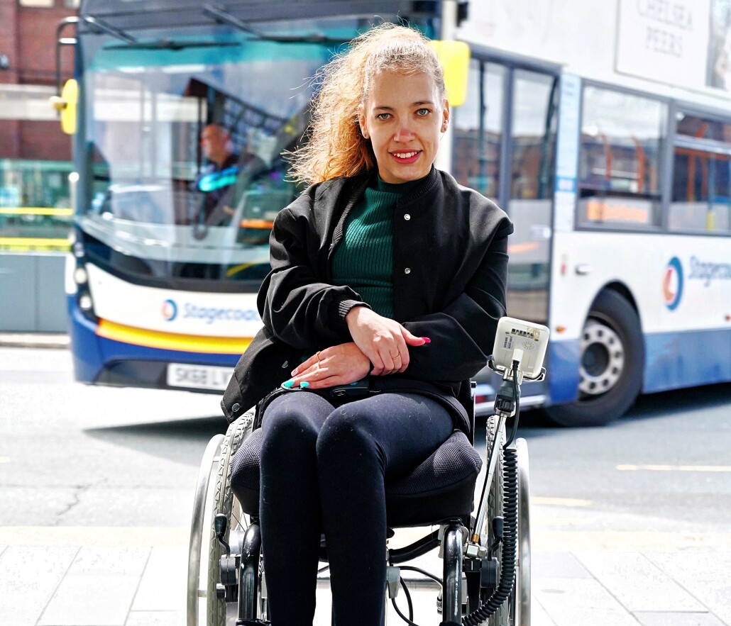 A young woman in a wheelchair at a bus station.