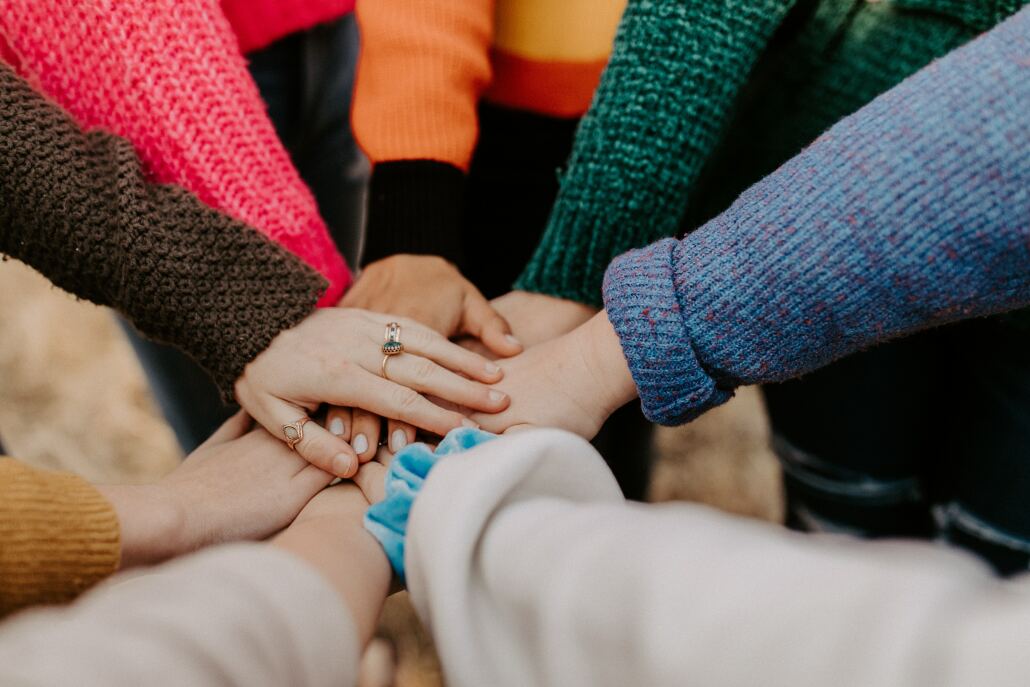 A group of people's hands put together on top of each other in the middle.
