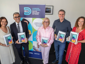 Metro Mayor Steve Rotheram with partners, holding boxed digital tablets. They are all smiling at the camera.
