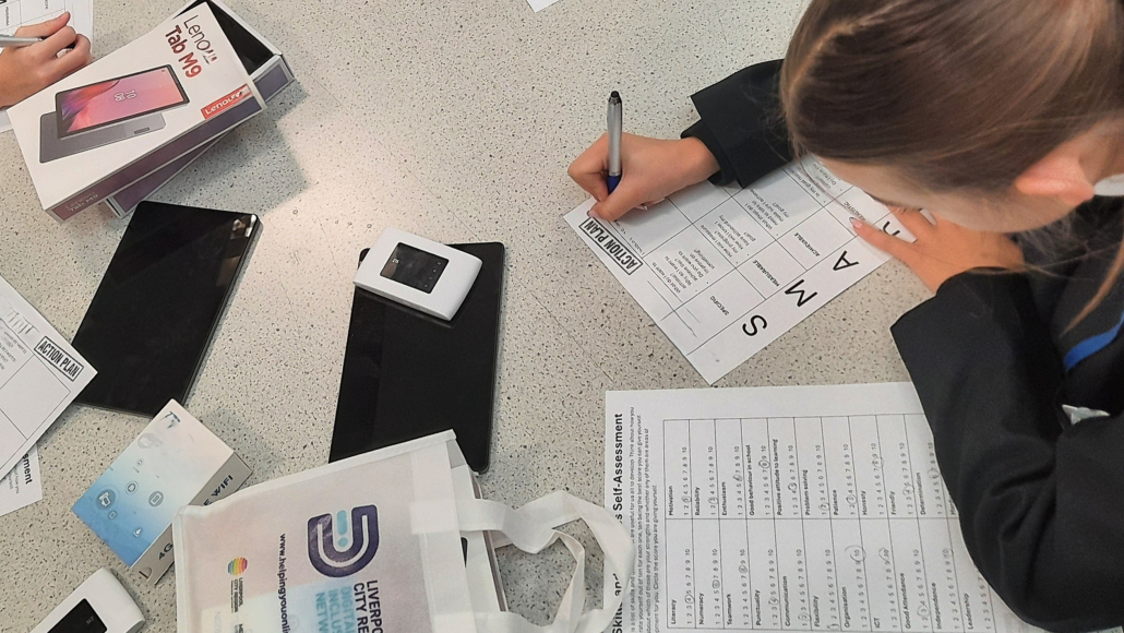 Young person leaning over some papers at a desk.