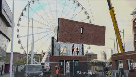 The Future Homes September House being constructed on the waterfront. Picture shows a wall of the house being lowered by a crane in front of Liverpool's big wheel.