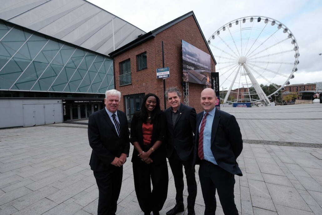 L-R Cabinet Member of the Combined Authority for Housing and Leader of Knowsley Council, Cllr Graham Morgan, Minister for Energy Consumers Miatta Fahnbulleh, Mayor of the Liverpool City Region Steve Rotheram and Liverpool City Council Leader and Lead Member for Innovation at Liverpool City Region Combined Authority, Cllr Liam Robinson all stand in a row with the zero bills house behind them on the Liverpool waterfront.