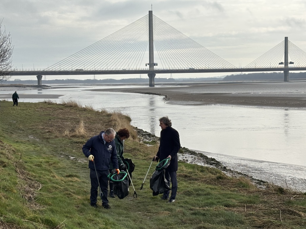 People litter picking along the edge of a river.