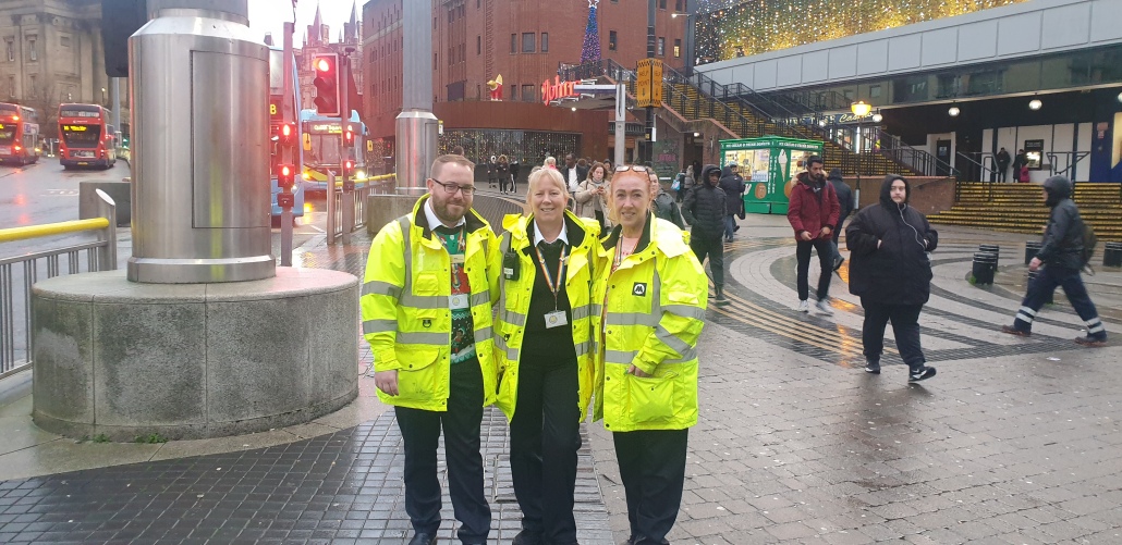 Three members of the bus team at the bus station all wearing their high vis coats