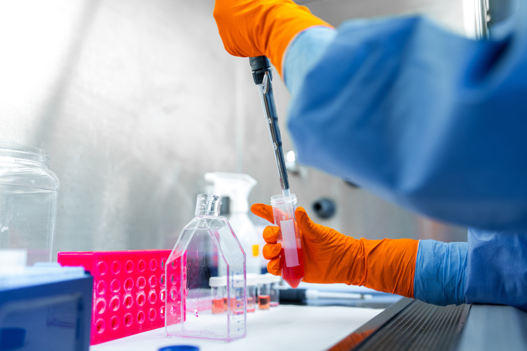 A scientist wearing PPE using a dropper to place substances in a test tube