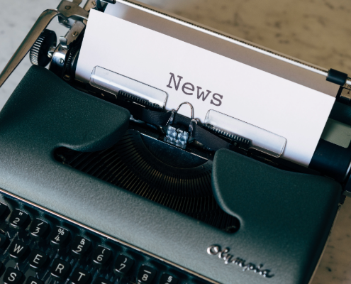 A typewriter with a piece of paper coming out of it. The piece of paper says 'news'.