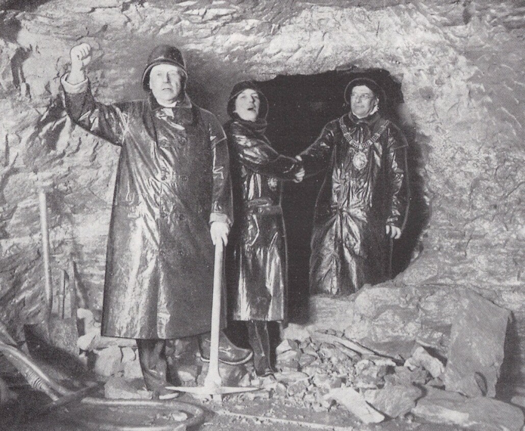 Men wearing waterproof clothing stand a the breakthrough of the Queensway Tunnel when Wirral and Liverpool met during it's construction 