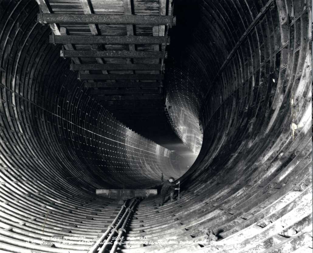 A photo looking through the tunnel at the vast space while a man works in the distance.