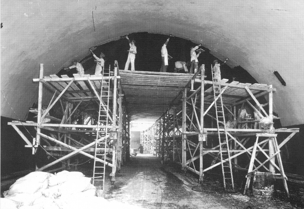 Construction of the Queensway Tunnel showing men on scaffolding working on it by hand.