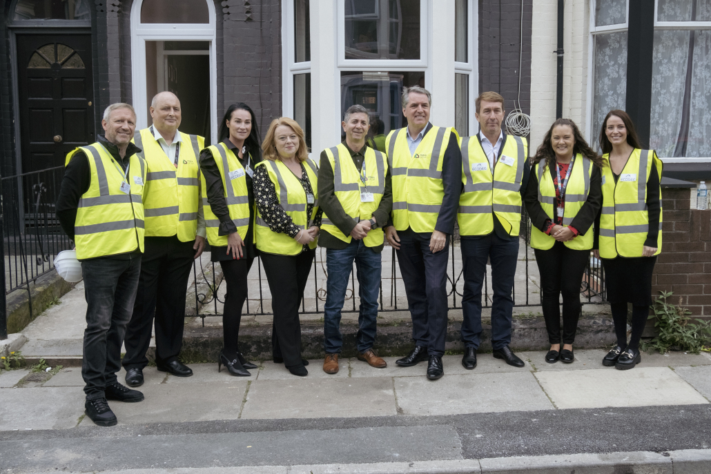 Mayor Steve Rotheram stands with a group of people outside a retrofitted home in high vis jackets