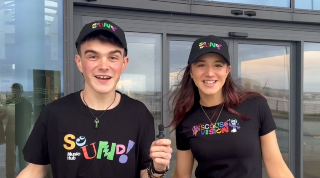 Scousevision presenters James and Sophie look at the camera smiling
