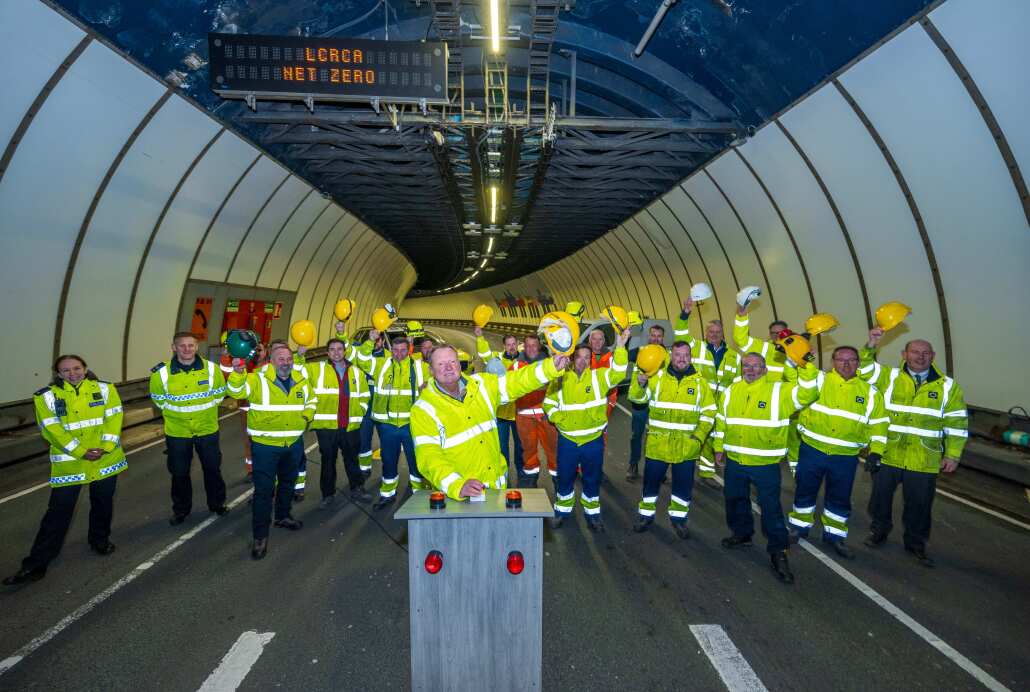Workers in hi-viz jackets celebrate the lights switch-on in the Mersey Tunnel
