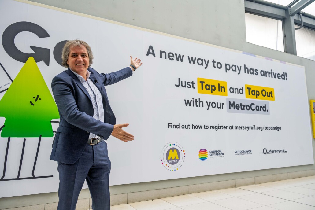 Mayor Steve Rotheram standing infront of a large advertising banner for the new Tap & Go ticketing system